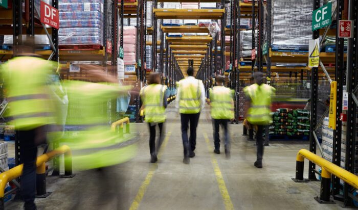 Pracownicy centrum logistycznego na tle regałów
